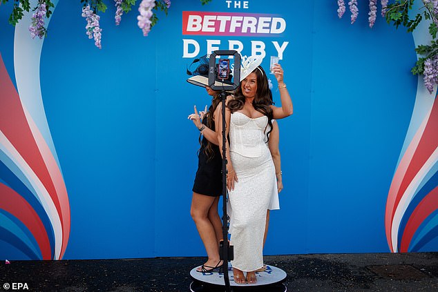 Strike a pose: A pair of visitors have their picture taken as they arrive to watch the races