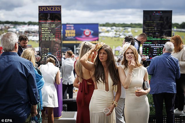 Place your bets: Two racegoers ponder which horse to back for the upcoming event