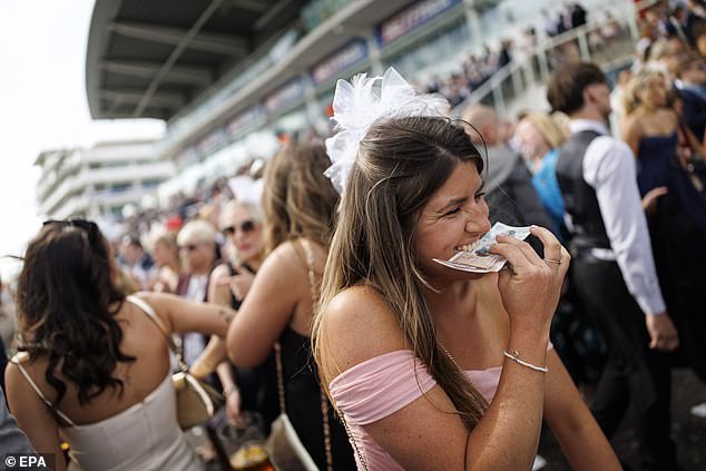 Bite of the action: A woman smiles as she holds her winnings at today's Epsom Derby