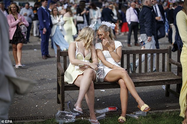 A pair of friends rest on a bench wearing sandals after a day out at the races