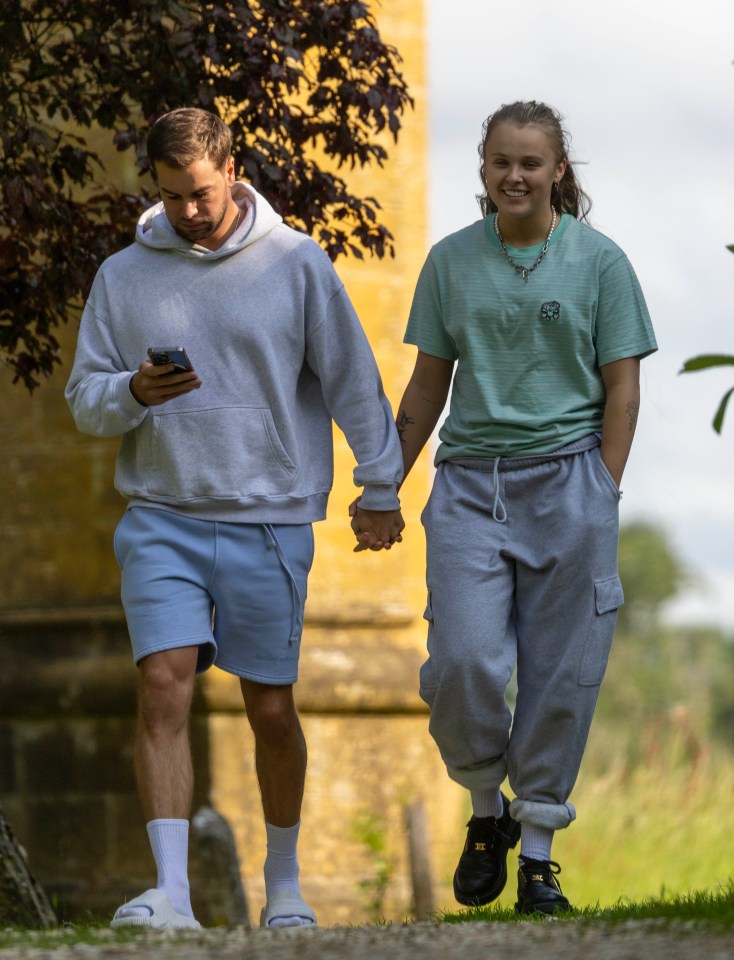 JoJo Siwa and Chris Hughes holding hands and walking.