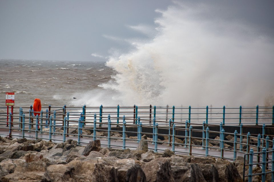 Strong onshore winds causing large waves to crash over a breakwater.
