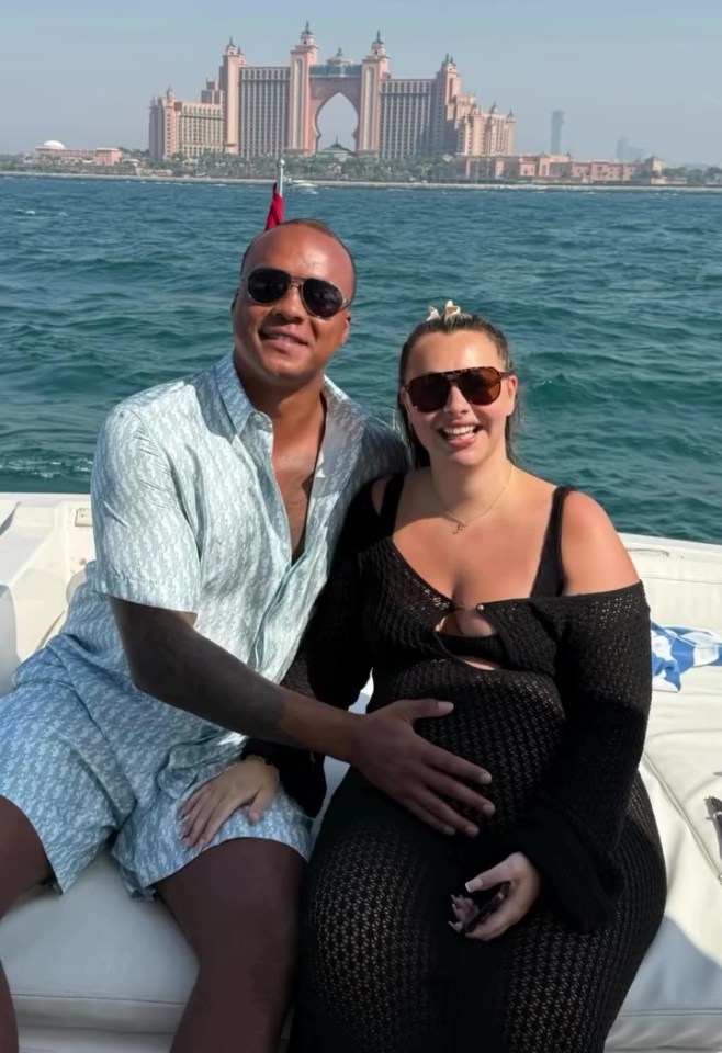 Pregnant woman and man on a boat with a large hotel in the background.