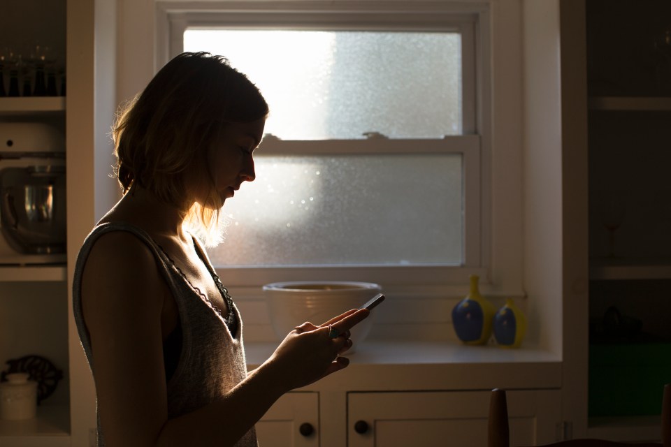 Silhouette of a young woman looking at her smartphone.