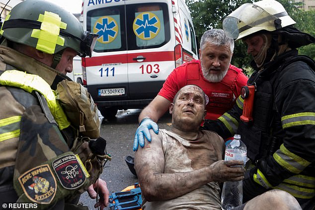 Rescuers and a paramedic speak with an injured man after he was released from debris of a building hit by a Russian drone strike