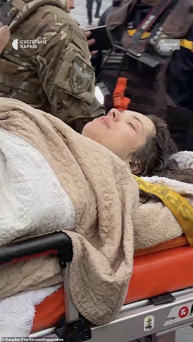 Rescuers carry Maria Simonenkova, 26, who spent several hours under a concrete slab that collapsed on her after the strike