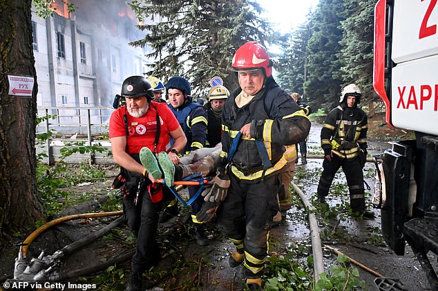 Rescuers carry a wounded person out of the ruins of a civilian plant following Russian powerful attacks on the Ukrainian city of Kharkiv