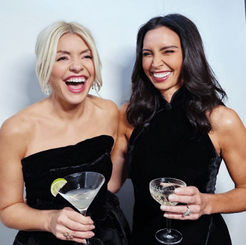 Holly Willoughby and Christine Lampard smiling and holding cocktails.