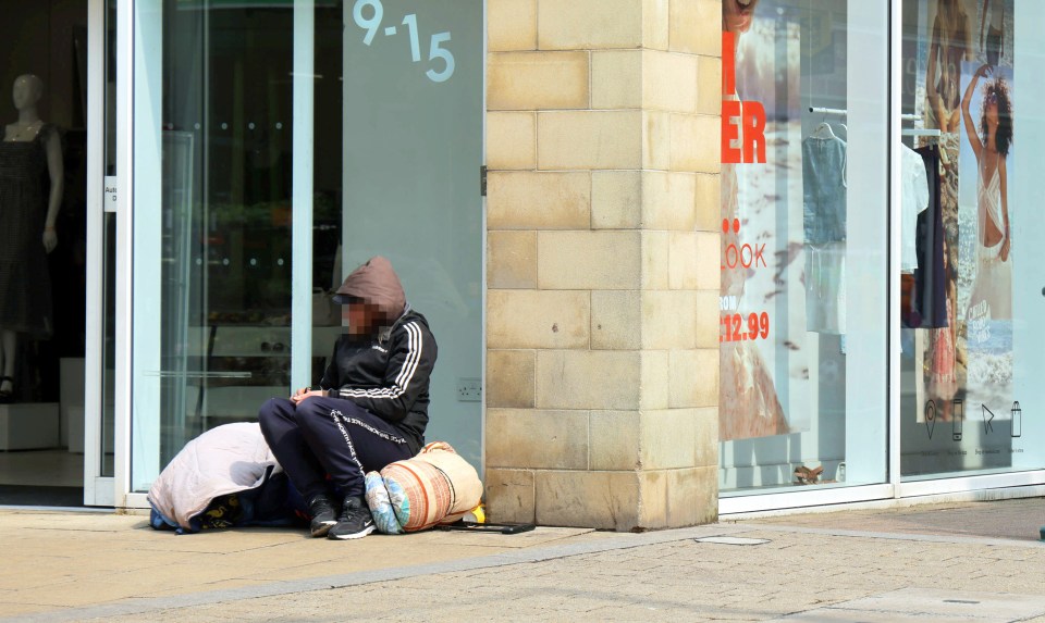 Person sitting on the ground outside a shop.