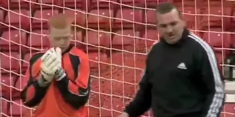 Soccer coach instructing goalkeeper.