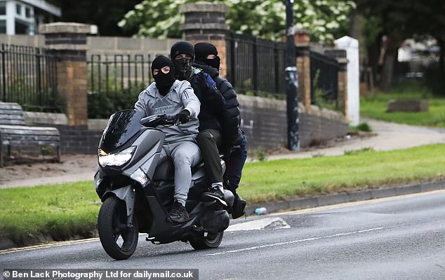 Three balaclava-clad youths ride on a motorbike through the streets of Bradford