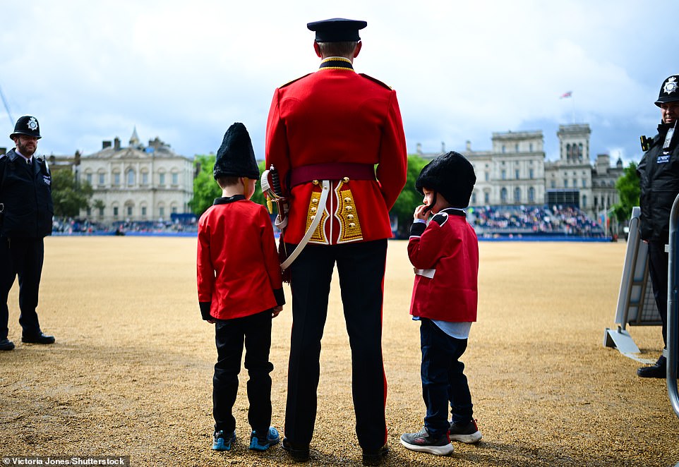 A soldier stands with two children dressed in uniform ahead of The Colonel's Review at Horse Guards Parade The Colonel's Review