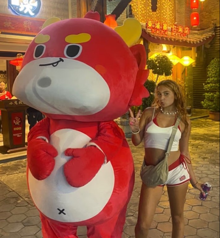 Woman posing with a large red dragon mascot.