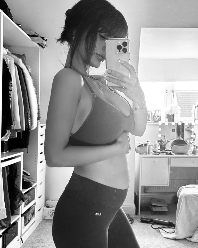 Black and white photo of a pregnant woman taking a selfie.