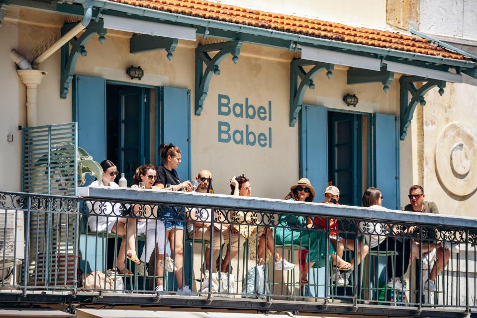 People sitting at tables on the terrace of the Babel Babel cafe.
