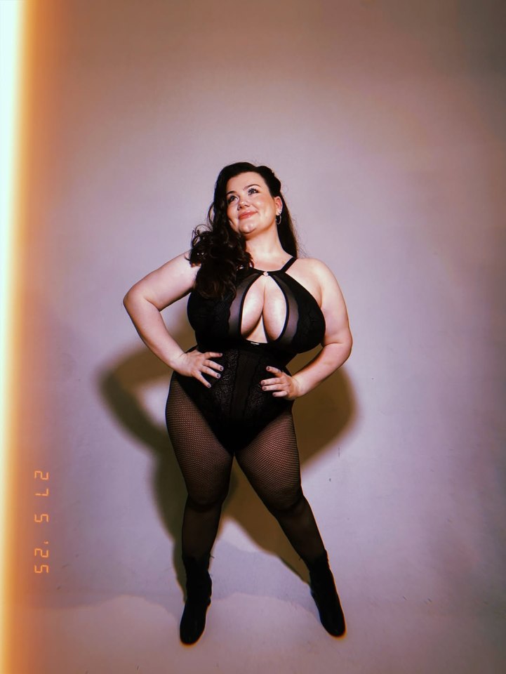 Portrait of a plus-size woman in a black lace bodysuit and fishnet stockings.