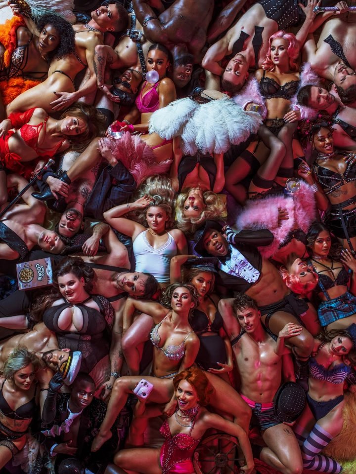 Large group of burlesque performers lying on the floor.