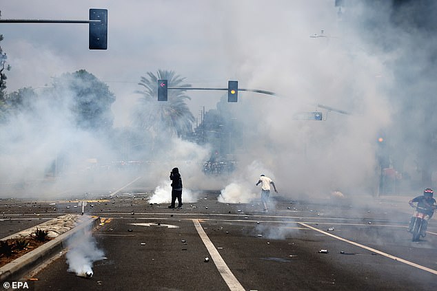 Protesters run through tear gas fired by federal agents after a raid was conducted by ICE