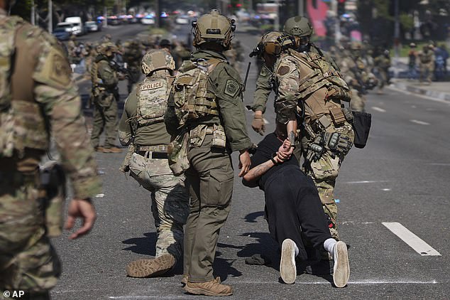 Police detain a man during a protest in the Paramount section of Los Angeles