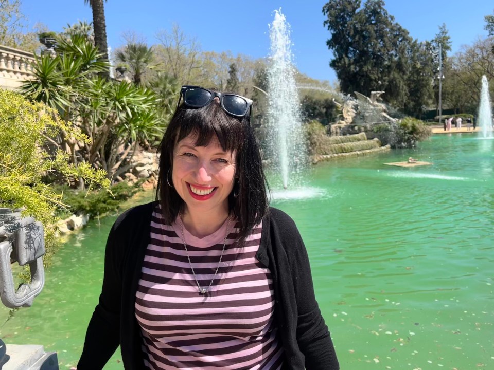Woman in striped shirt by a fountain.