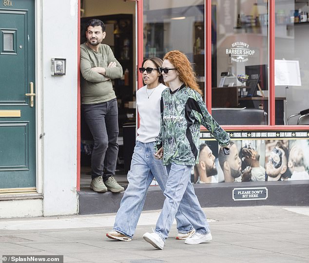 For the outing, Jess cut a quirky display in an over-sized black green baggy sports top which she paired with loose-fitting blue jeans