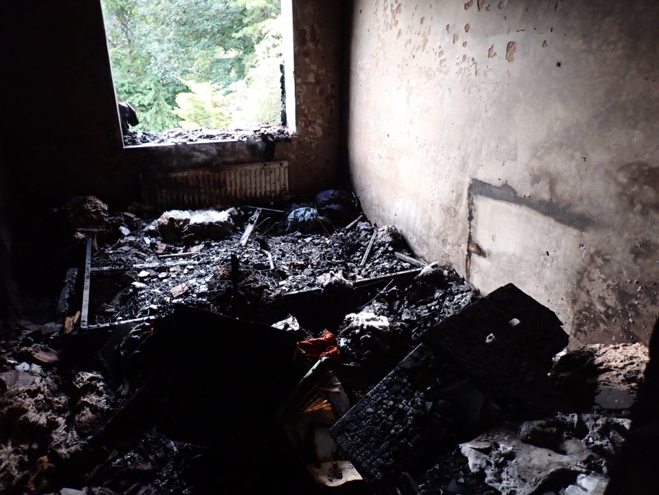 Fire damage inside a room, with debris and a partially collapsed ceiling.