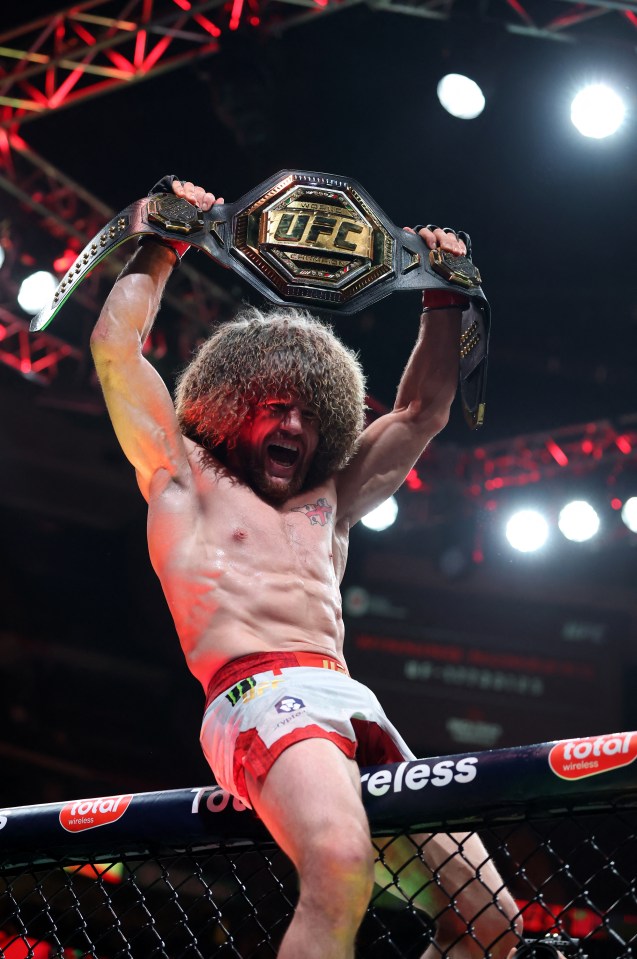 Merab Dvalishvili holding up the UFC championship belt after a victory.
