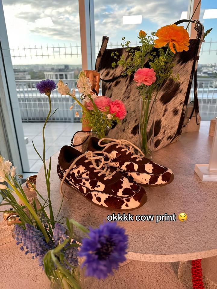 Cow print sneakers and handbag displayed with flowers.