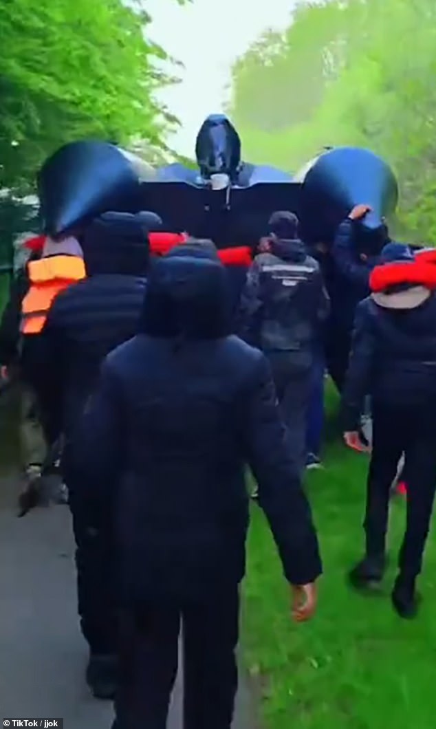 Pictured: a group of people believed to be migrants carry a boat which may be used to cross the Channel. The social media footage comes as Conservative leader Kemi Badenoch last night demanded the freedom to deny migrants benefits ¿ a move currently restrained by European human rights laws