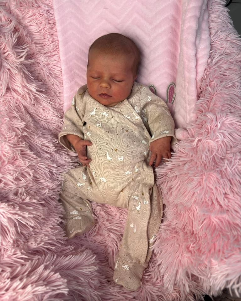Sleeping newborn baby on pink blanket.