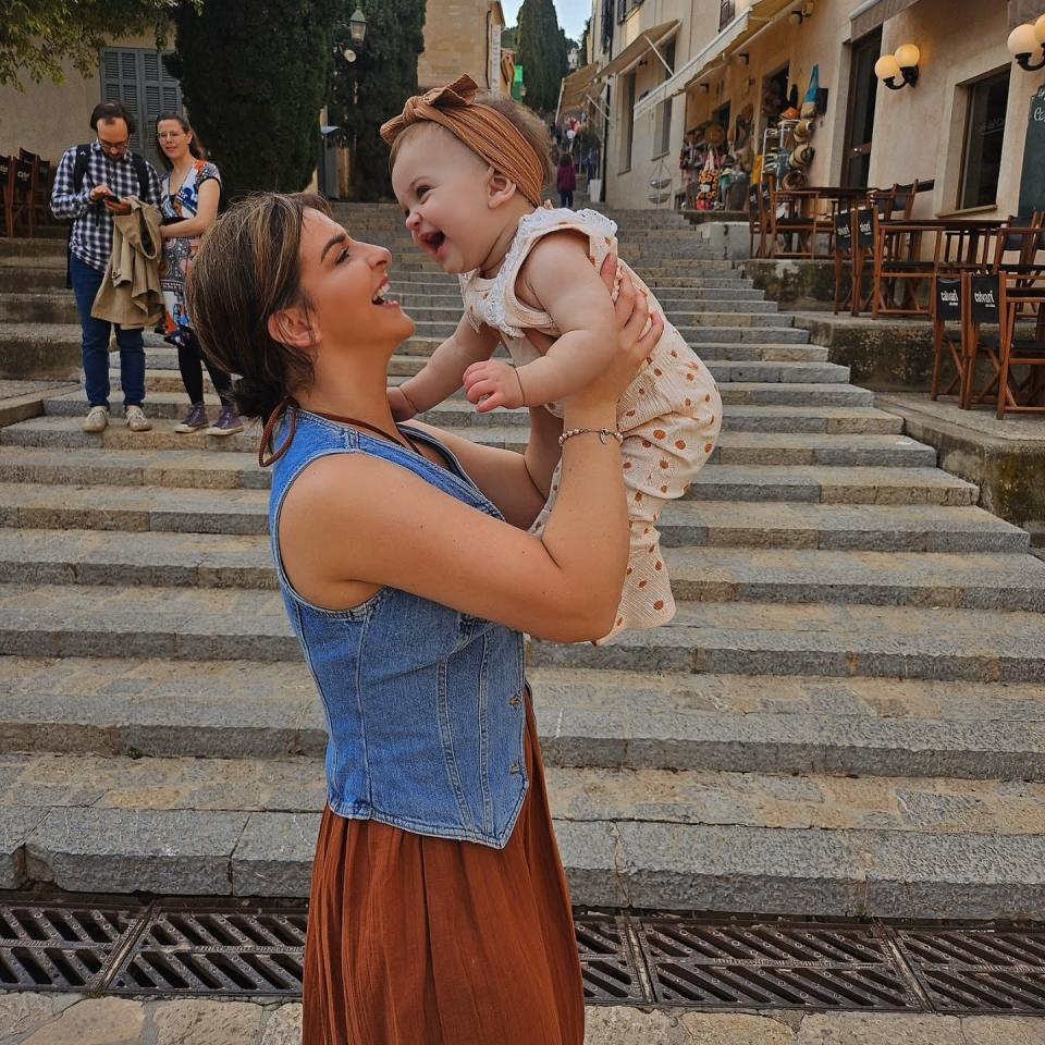 Woman holding up her baby daughter on stone steps.