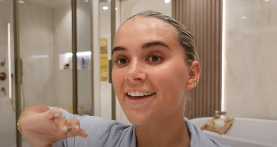 Woman in a bathroom talking to the camera.
