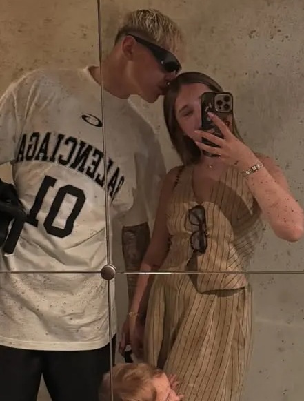 Mirror reflection of a man kissing a woman, with their toddler son standing between them.