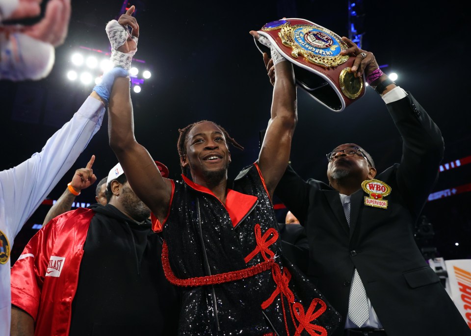 Keyshawn Davis celebrates a boxing victory, holding up a championship belt.