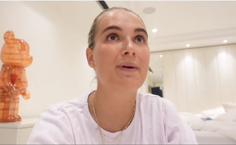 Woman speaking to camera in a bedroom.