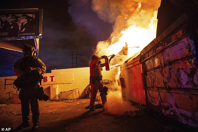 A law enforcement officer works to put out a fire during a protest in Compton, California, Saturday, June 7