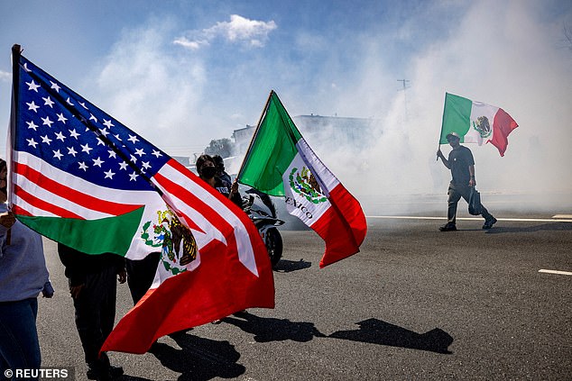 A man holds a Mexican flag during a standoff by protesters and law enforcement in Compton on Saturday