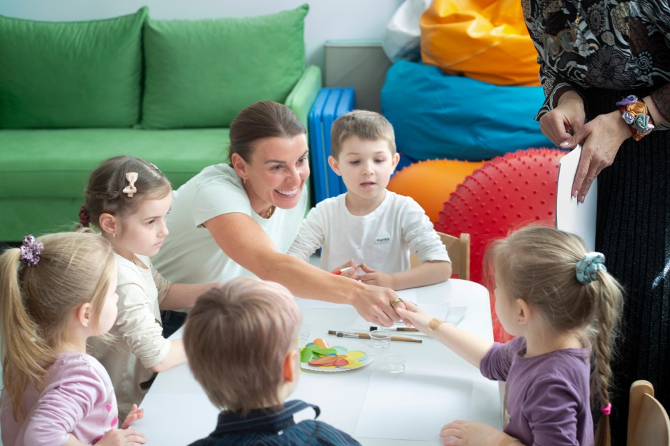 Coleen Rooney with children in a classroom setting.