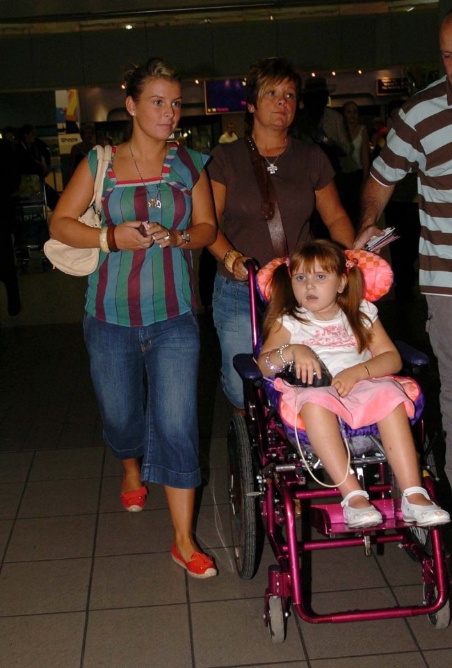 A girl in a wheelchair is pushed through an airport by her family.