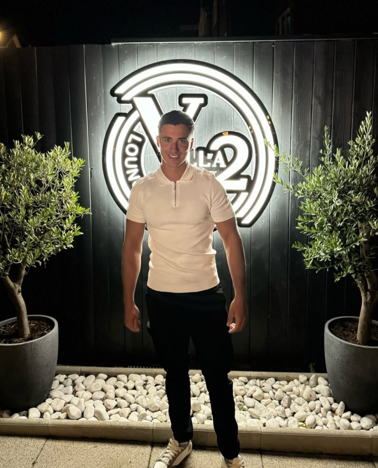 Man in white shirt and black pants standing in front of a Villa 2 Lounge sign.