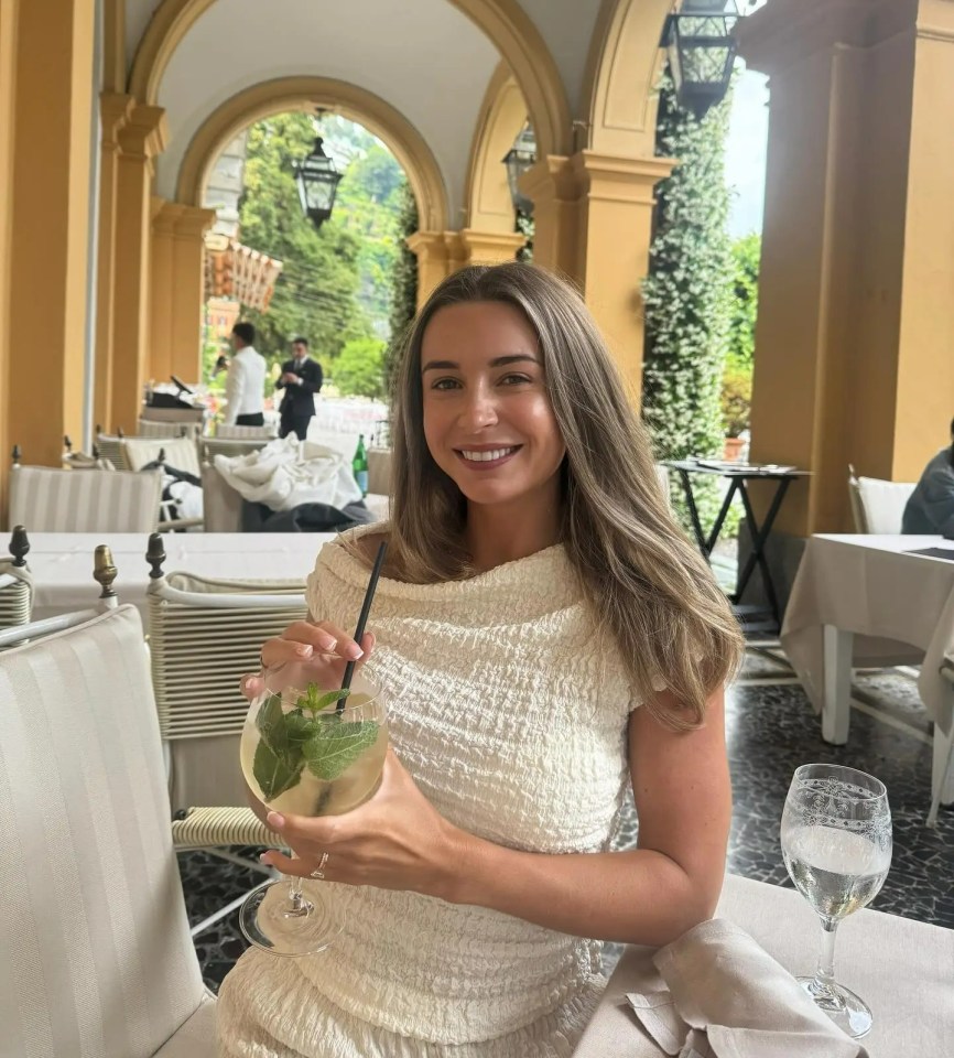 Woman in white top holding a cocktail in an outdoor restaurant.