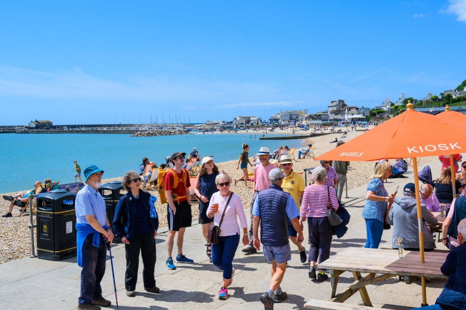 Crowds of people enjoying a sunny day at Lyme Regis beach in Dorset, UK.