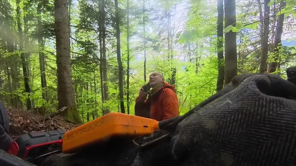 Man on a cell phone in a forest after a paragliding accident.