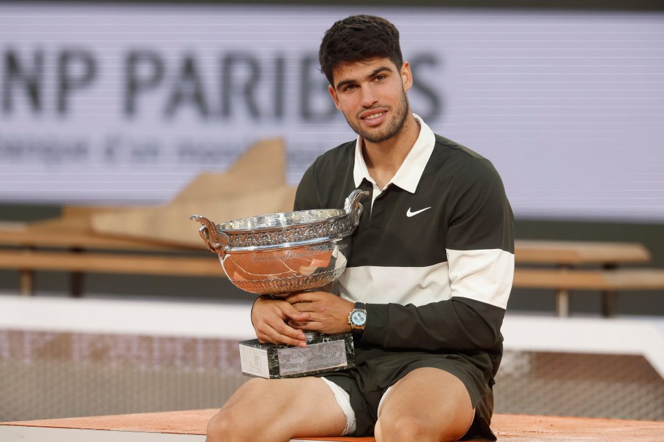 Carlos Alcaraz holding the Roland Garros trophy.