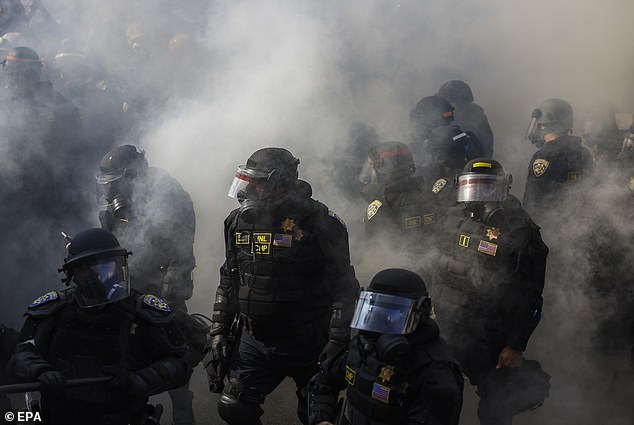 Officers covered in protective gear defend against rioters after after Trump issued an extraordinary directive vowing to 'liberate Los Angeles' from illegal aliens which have 'invaded and occupied a once great American city'