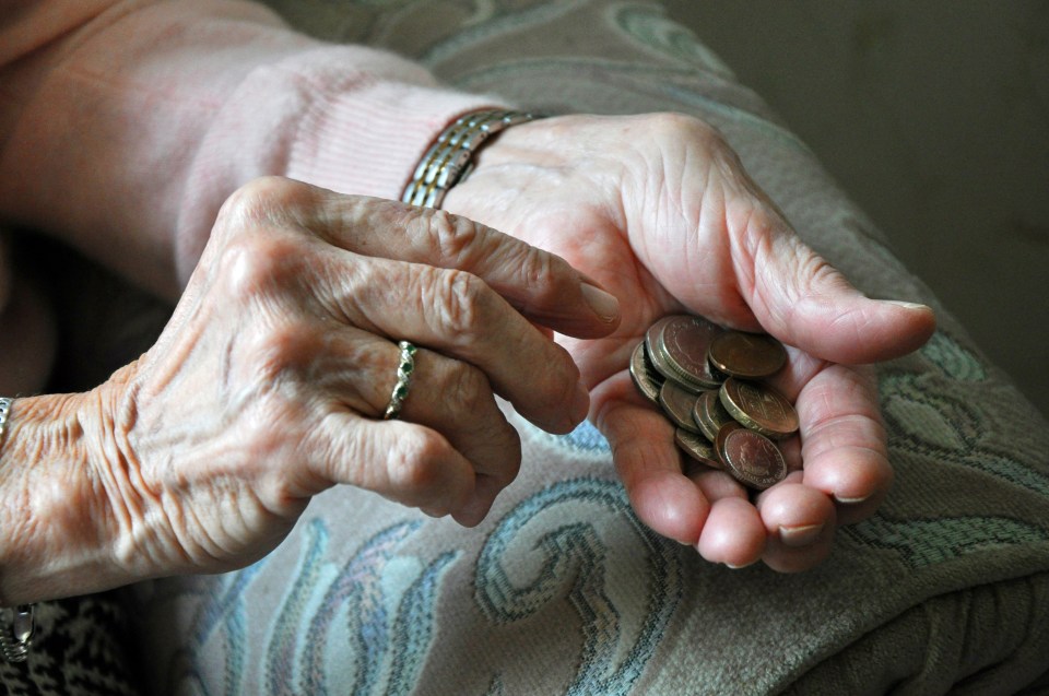 an elderly woman is holding a handful of coins