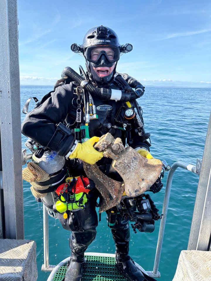 Diver holding recovered ship bell from 80-year-old shipwreck.