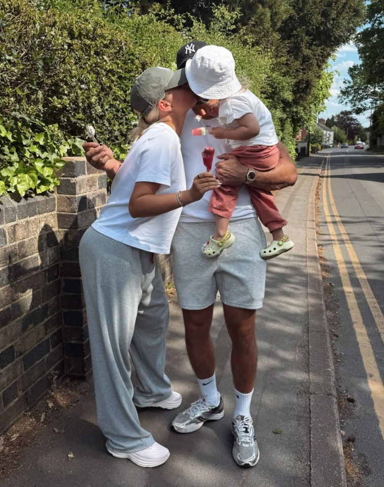 Couple kissing with their child holding ice pops.