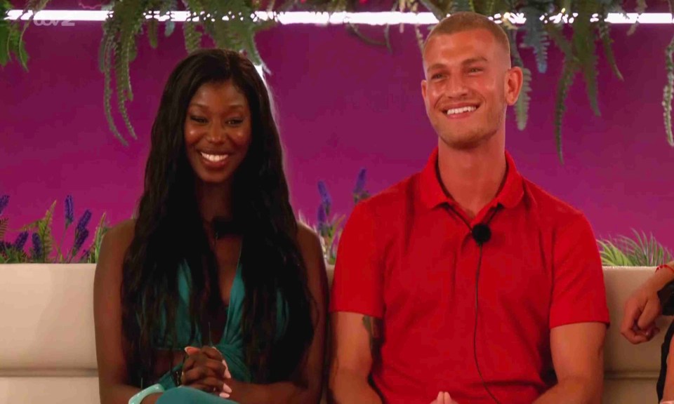 A man and woman smiling on a Love Island set.