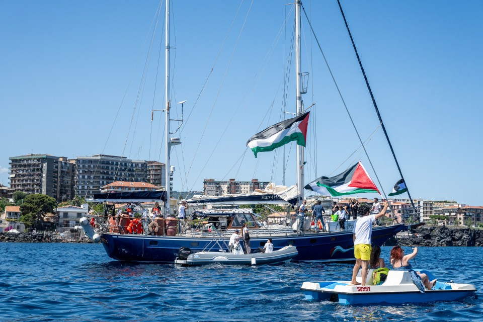 Sailboat with Palestinian flags and people on board.